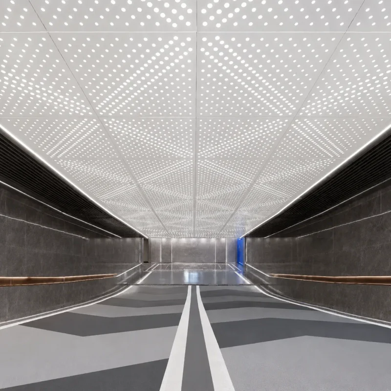 White perforated metal acoustic ceiling panels with round holes in a commercial corridor