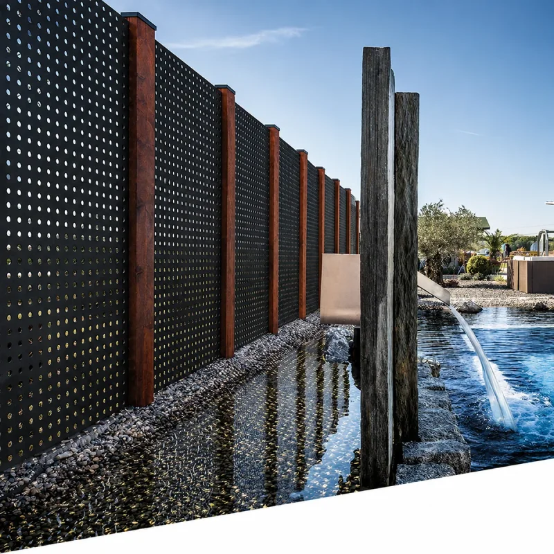 Black perforated metal privacy screen panels beside a landscaped water feature