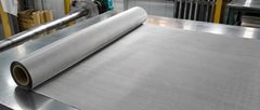Stainless steel filter mesh roll partially unrolled across a metal worktable