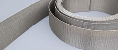 Close-up of a coiled stainless steel reverse Dutch weave strip showing its dense woven surface and edges