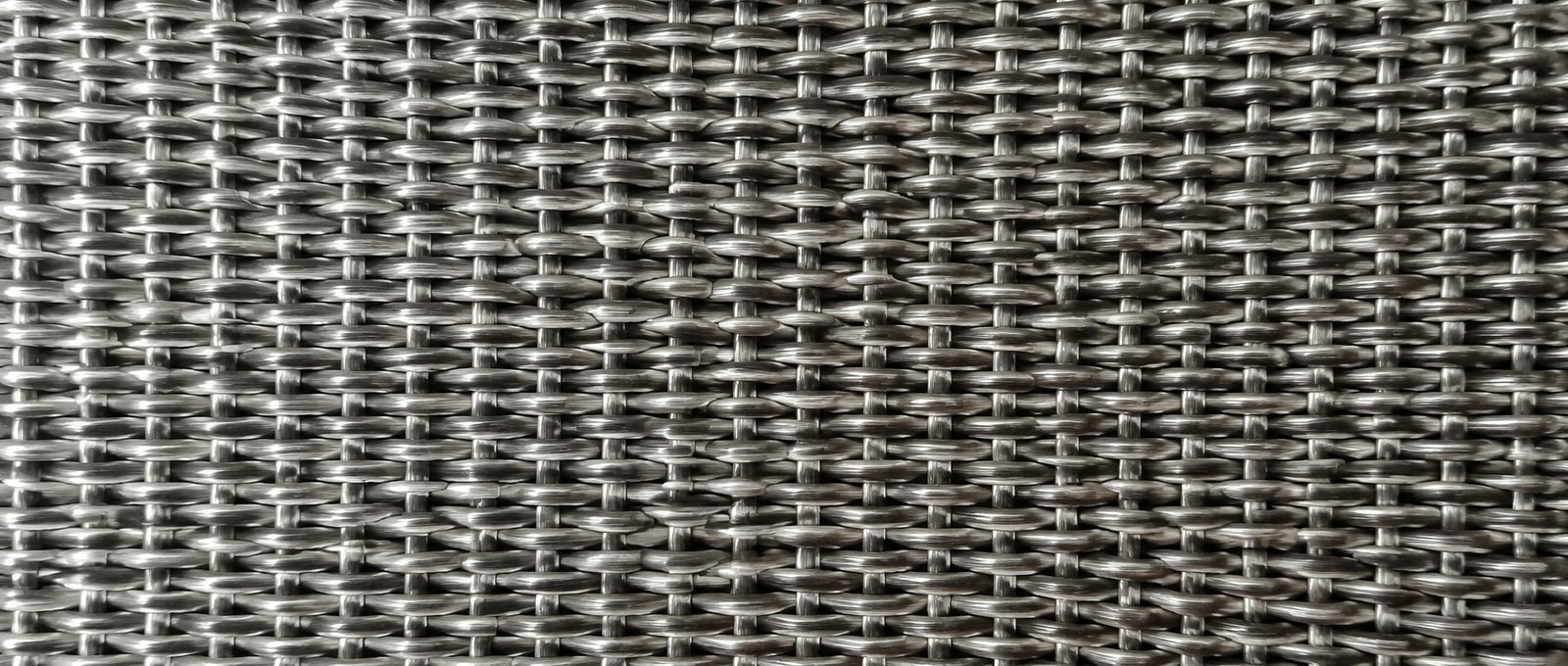 Close-up of silver stainless steel woven wire mesh showing dense interlaced wires and surface texture