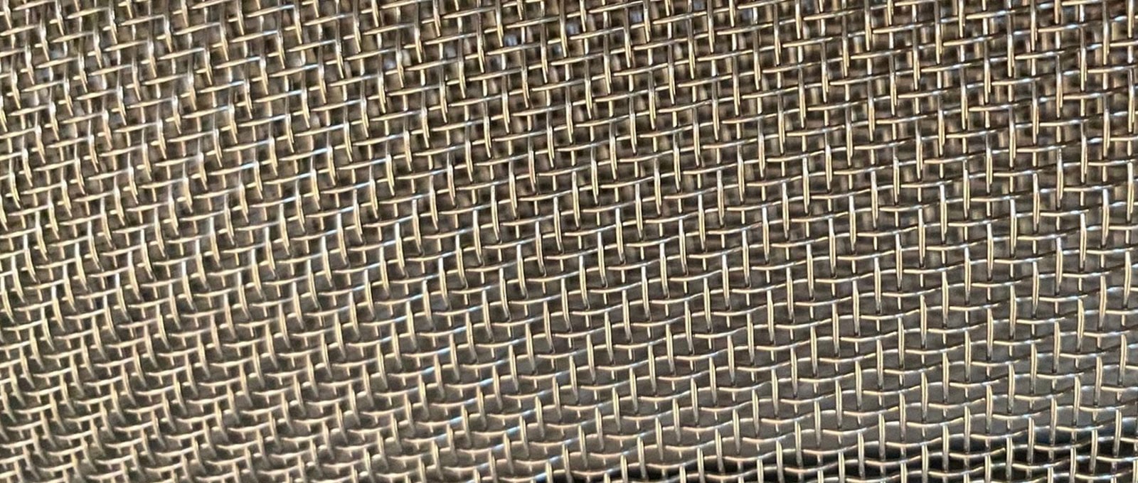 Close-up of stainless steel twill weave wire mesh showing staggered wire intersections