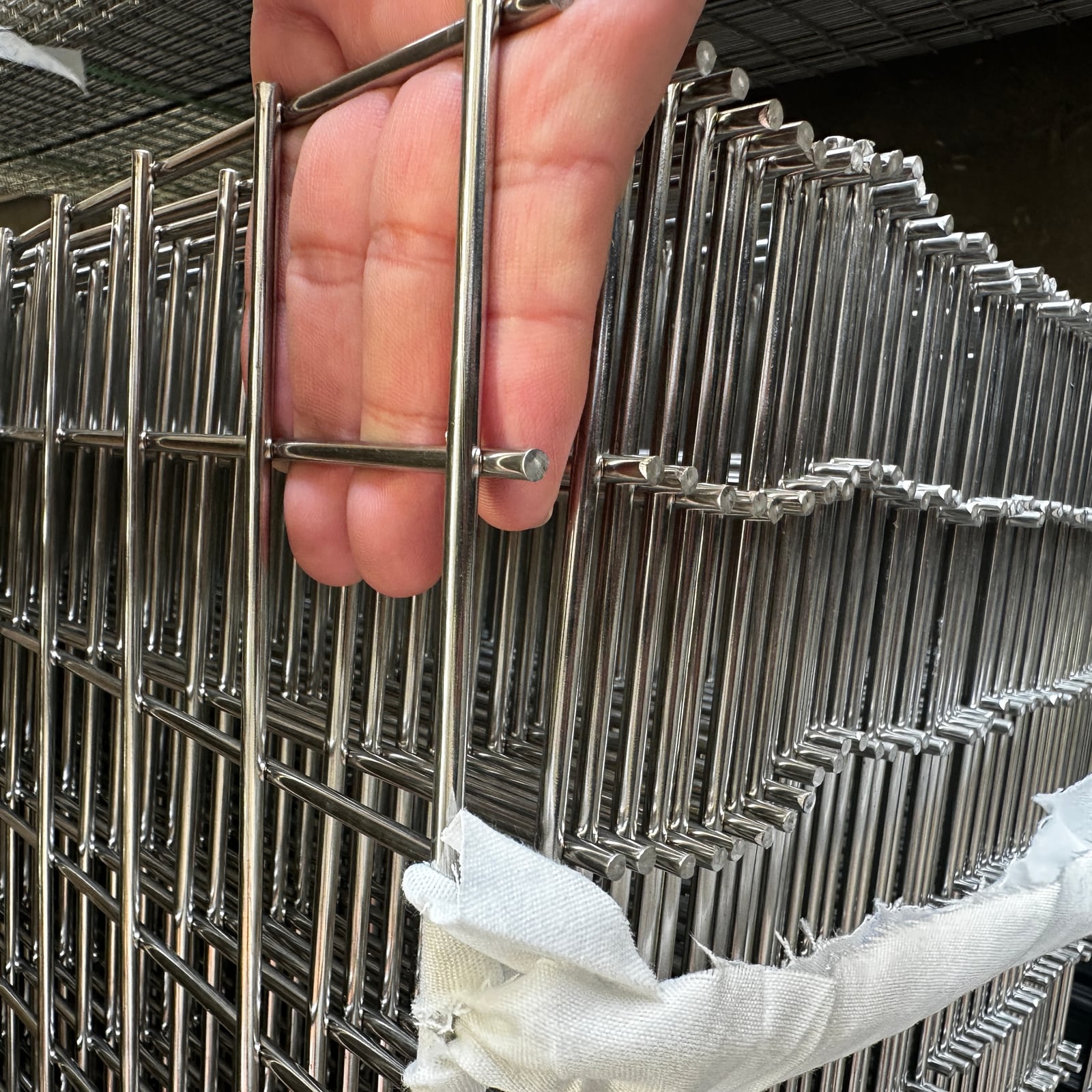 Hand-held stainless steel welded wire mesh panel showing welded intersections and wire ends