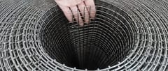 Stainless steel welded wire mesh roll with a hand-held sample showing uniform square openings